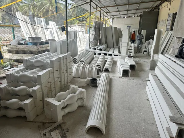 Finished white GRC balusters, fluted column shells and cornice lengths stacked in the yard of the manufacturing unit