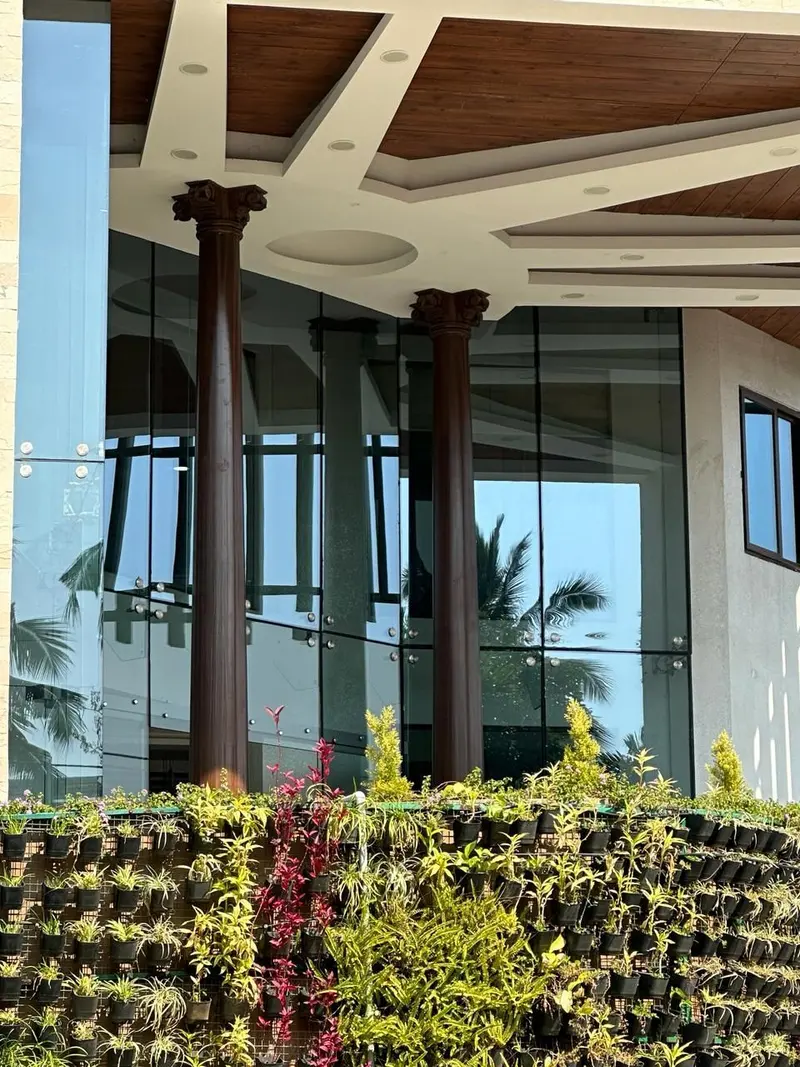 Columns at the glazed entrance of Aayakar Bhavan above a green wall