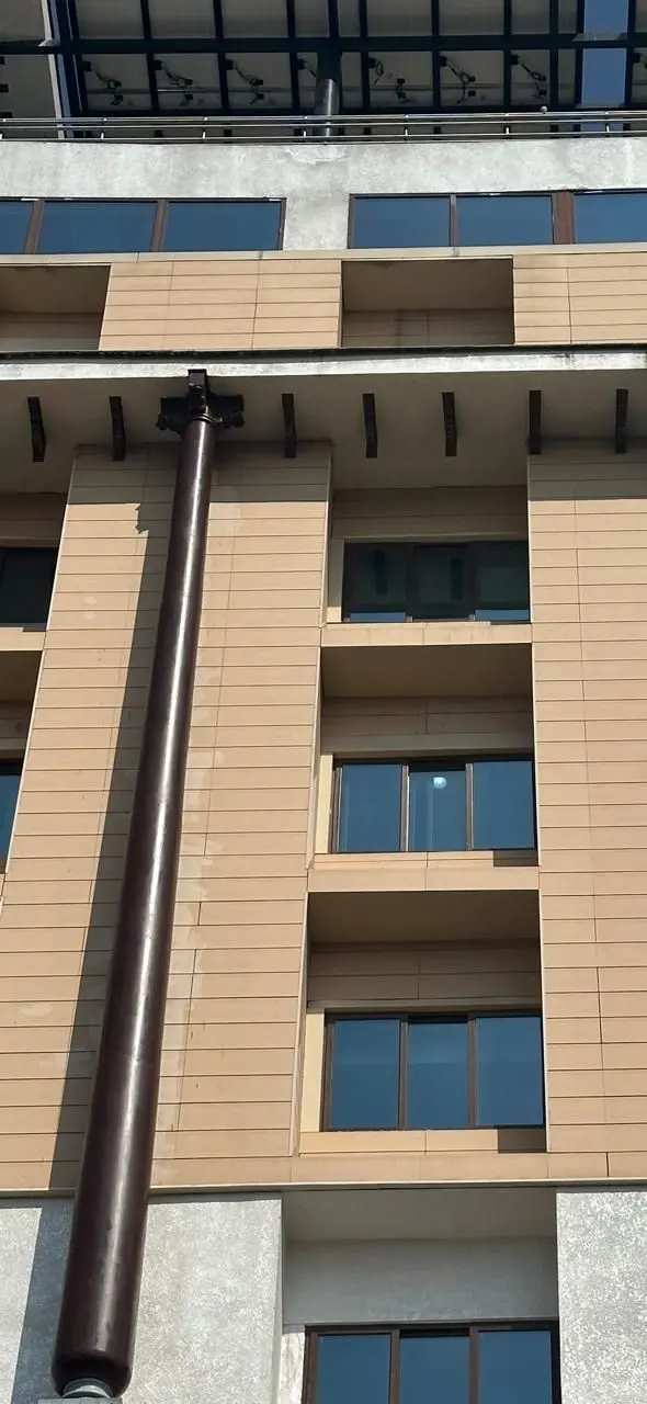 A column rising past the windows of Aayakar Bhavan to the brackets under the cornice