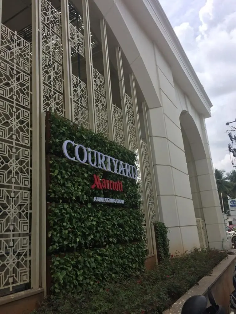 Tall geometric jali screens beside the Courtyard by Marriott sign and green wall