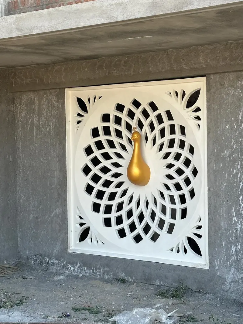 White jali panel with a radiating floral pattern and a gilded peacock, ISKCON temple, Coimbatore